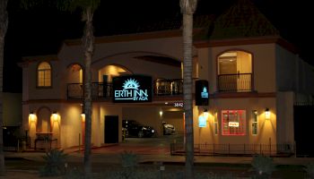 A two-story building at night with a sign reading "Erth Inn by Aga" and another sign with "office" illuminated. Two cars are parked inside.