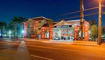 A well-lit hotel building at night with a visible sign reading 