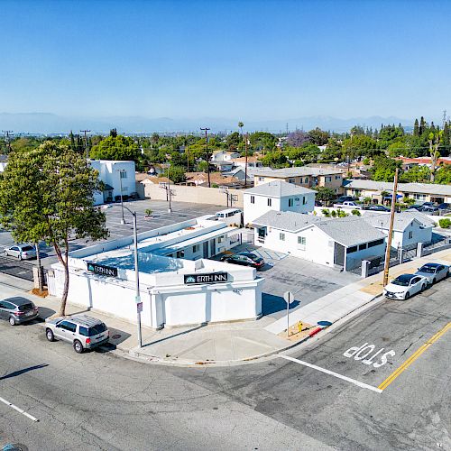 This image shows a small urban intersection with white buildings, cars parked along the streets, and a visible 