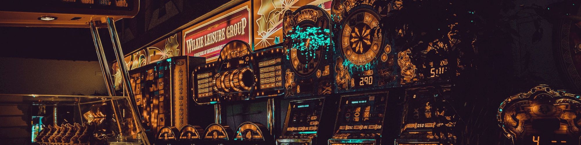 The image shows a dimly lit arcade with various gaming machines, chairs, and decorative lights, suggesting a retro or vintage-themed setting.