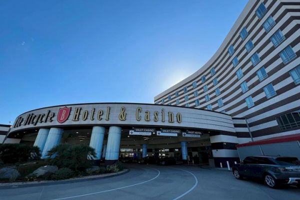 The image shows the entrance of a hotel and casino. The building is large and curved, featuring prominent signage that reads, 