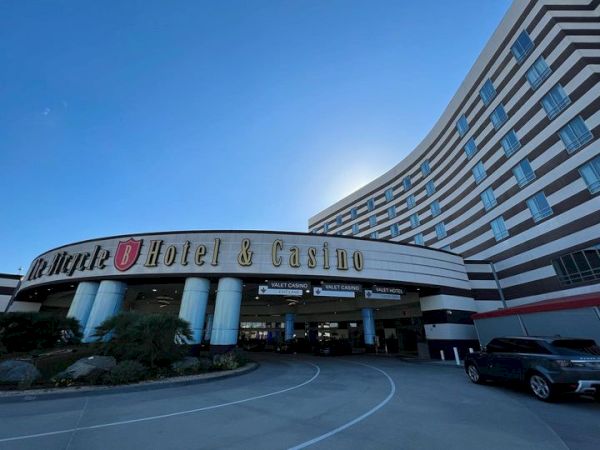 The image shows the entrance of a hotel and casino. The building is large and curved, featuring prominent signage that reads, "Hotel & Casino."