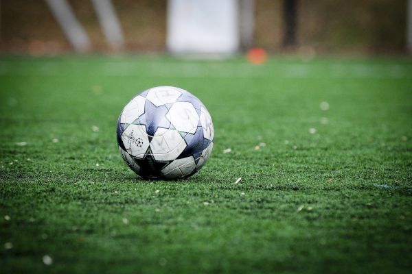 A soccer ball rests on a green grass field, ready for play in an outdoor setting.