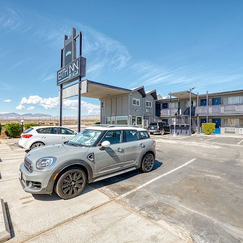 A parking lot with several cars is in front of a two-story motel building and a sign that reads 