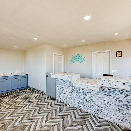 This image shows a modern reception area with a marbled front desk, herringbone-patterned flooring, and cabinets against the far wall, ending the sentence.