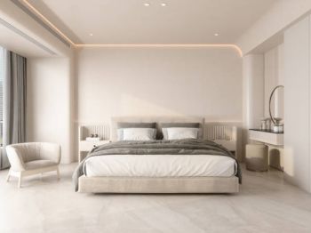 A modern bedroom with a large bed, gray bedding, a chair by the window, minimal decor, and soft ceiling lighting.