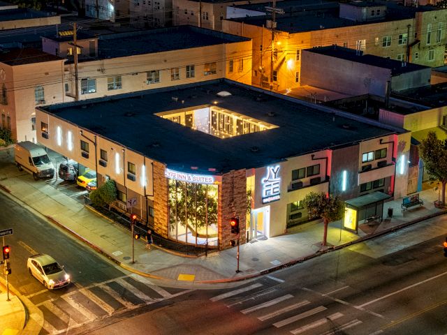 Aerial view of a hotel building at night with neon signs and a flat roof.
