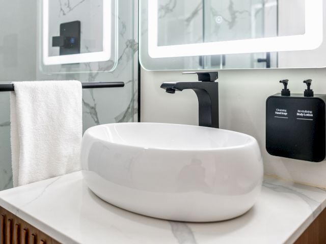 A modern bathroom sink with a white bowl, black faucet, and marble countertop.