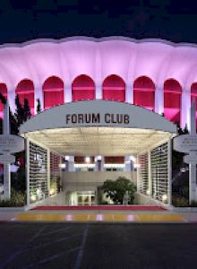 The image shows a well-lit, circular building with an illuminated canopy reading 