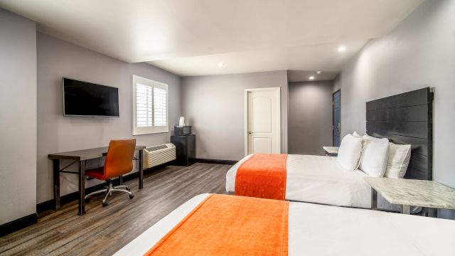 A standard hotel room with two beds, a desk, and a TV.
