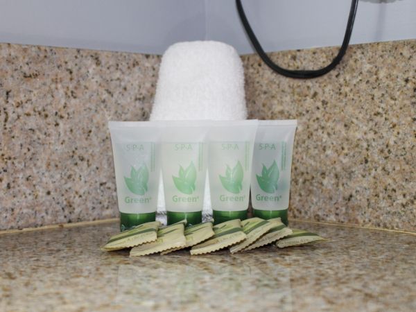 The image shows four tubes of "SPA Green" toiletries and several wrapped soap bars, placed on a speckled countertop under a white towel.