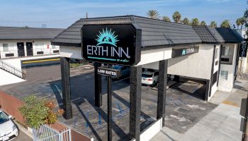 The image shows a motel called "Erth Inn" with a sign reading "Low Rates" in front of the building under a clear blue sky.