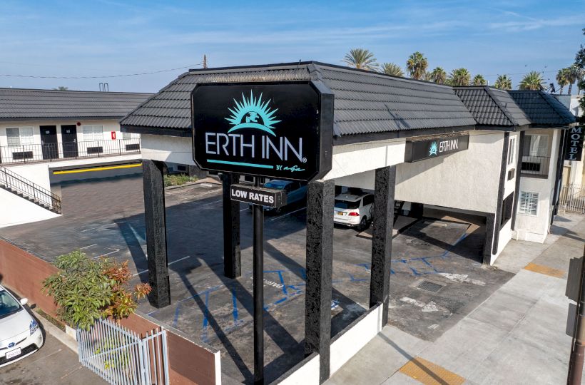 The image shows a motel called "Erth Inn" with a sign reading "Low Rates" in front of the building under a clear blue sky.