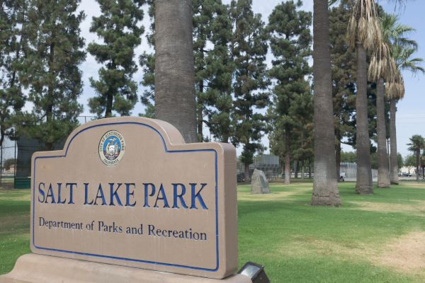 A sign for Salt Lake Park in front of tall trees and green grass, part of the Department of Parks and Recreation.