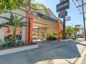 The image shows the entrance of a building labeled "Nite Inn" with a car parked under the canopy and palm trees in the surroundings.