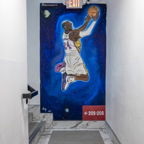 A street-art mural shows a basketball player soaring in a blue space scene above a hallway sign reading 205&ndash;208.