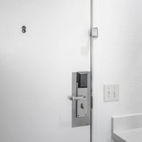 A white interior wall shows a metal door latch/lock near electrical outlets and switches.